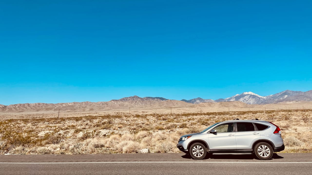 Silver SUV beside an open road and mountains